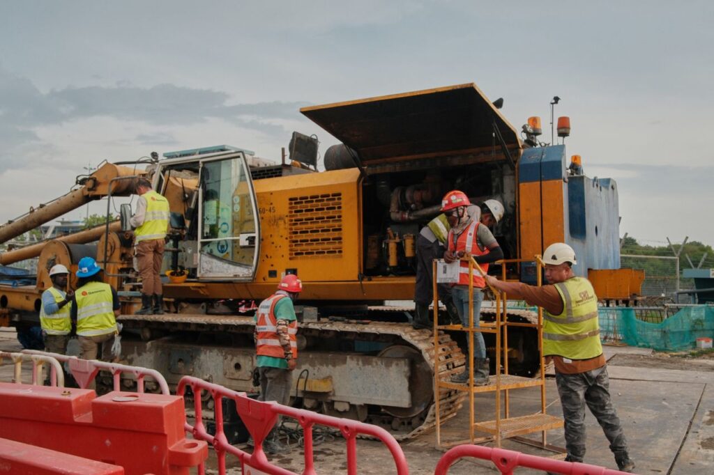 Group of construction workers handling machinery at a worksite with safety gear.